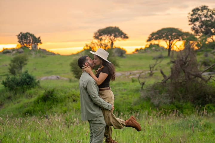 A couple on an exclusive private game drive watching a herd of elephants by a baobab tree in Tarangire National Park.